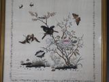 une photo représentant un tableau avec des oiseaux et des fleurs, dans un cadre