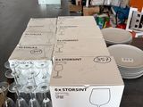 boxes of wine glasses and plates on a table in a cluttered room