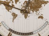 a close up of a clock with a world map on it