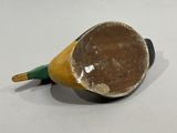 a small wooden object with a green handle on a white surface