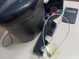 une cafetière noire posée sur une table, à côté d'une calculatrice