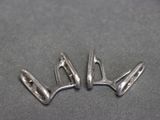 two silver metal hooks on a gray surface with a black background