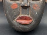 a close up of a wooden mask on a black background