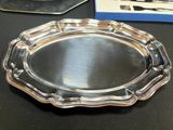 a silver plate on a table with a knife and fork in the background