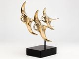 a gold sculpture of three birds on a black stand