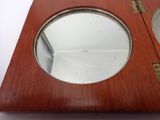 a small wooden clock with a mirror on it
