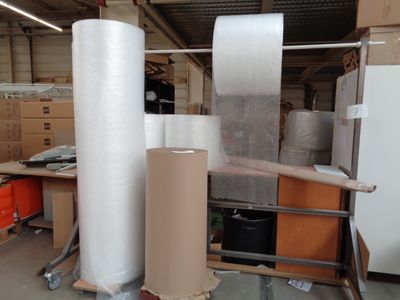 many rolls of plastic sitting on a cart in a warehouse