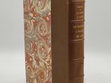 un vieux livre à la couverture marron posé sur une table blanche