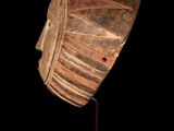 a close up of a wooden mask on a black surface
