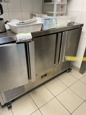 un plan de travail en acier inoxydable dans une cuisine professionnelle, avec une poubelle
