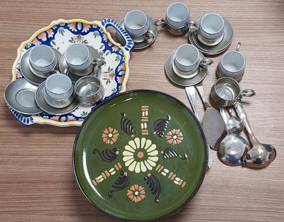 une assiette verte ornée d'un motif floral, à côté d'une assiette sur laquelle sont posées des cuillères et des repose-cuillères