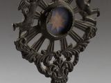 une petite horloge posée sur un socle et surmontée d'une couronne