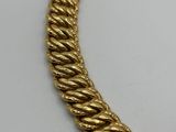 a gold necklace with a twisted design on a white surface