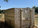 an old outhouse sitting in the middle of a field with a tree in the background