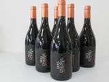 six bottles of red wine are lined up on a table