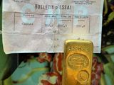 un lingot d'or dans une boîte en fer-blanc, avec une étiquette indiquant son prix