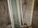 a broken glass shower door in a bathroom with a lot of debris