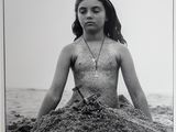 photographie en noir et blanc d'une femme assise sur le sable, à la plage