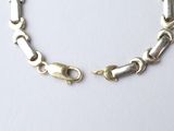a close up of a silver chain bracelet on a white surface