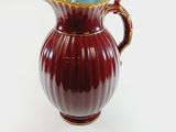 a red and blue vase with a gold handle on a white surface