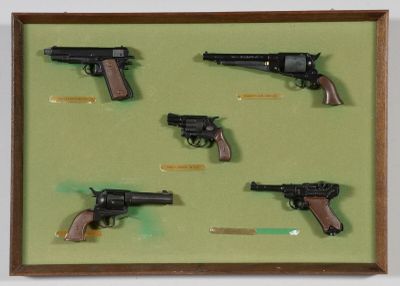 une photo montrant un ensemble d'armes à feu présentées dans un cadre en bois