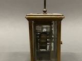 an antique brass clock with a glass case on a gray background