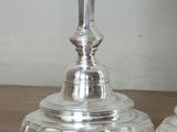 pair of silver candlesticks on a wooden table with a white wall in the background