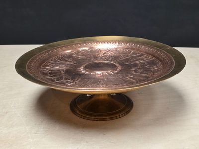 an antique brass plate with a flower design on it on a table