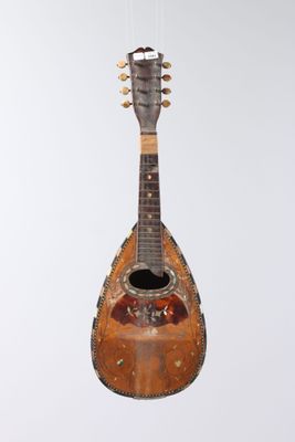 an old guitar hanging from a string on a white wall