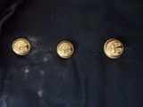 three gold buttons on a black jacket with a black background