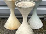 three cement vases sitting next to each other on the ground