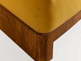 mustard colored leather chair with wooden legs and foot rests against a white wall