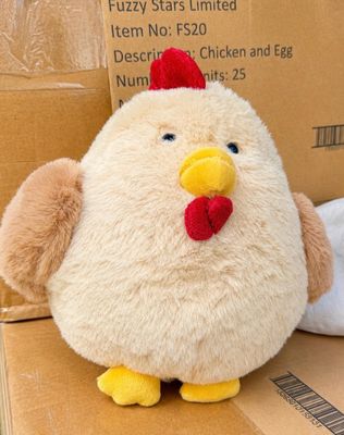 un poulet en peluche posé sur une boîte en carton