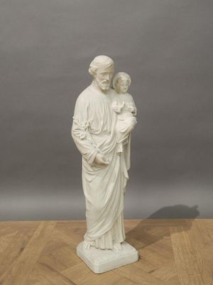 statue of a woman holding a child in her arms on a wooden floor