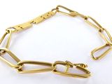 gros plan d'un bracelet en chaîne en or sur une surface blanche