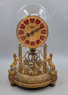une horloge placée sous un dôme de verre sur une table