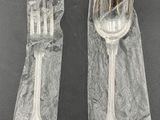 two forks and spoons wrapped in plastic on a table