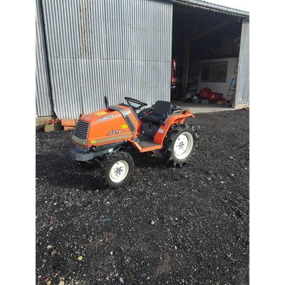 un petit tracteur orange garé devant un immeuble