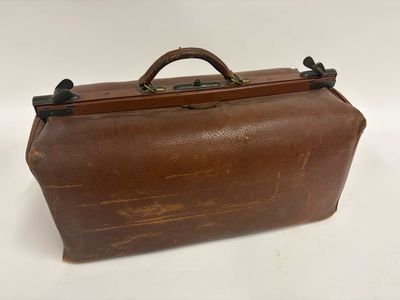 valise en cuir marron sur fond blanc, avec une poignée et une autre poignée