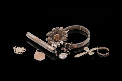 some silver jewelry is laying on a black surface with a black background