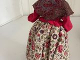 a small doll that is wearing a dress and a hat