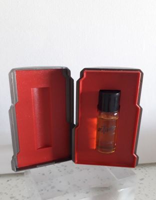 une boîte rouge contenant un petit flacon de parfum