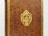 un livre en cuir marron avec des bordures dorées et un emblème doré