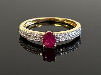 a close up of a ruby and diamond ring on a black surface