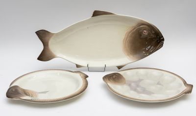 un plat en forme de poisson et deux assiettes sur la table