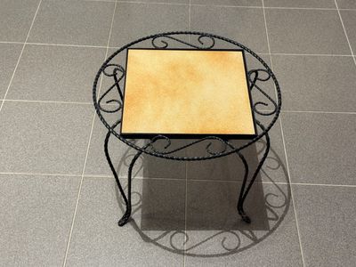 une petite table avec un plateau en carrelage posée sur un sol carrelé