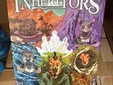 La boîte du jeu de société « Les Héritiers » est posée sur une boîte en carton