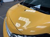 a yellow car parked in a parking lot with a number 5 on the hood