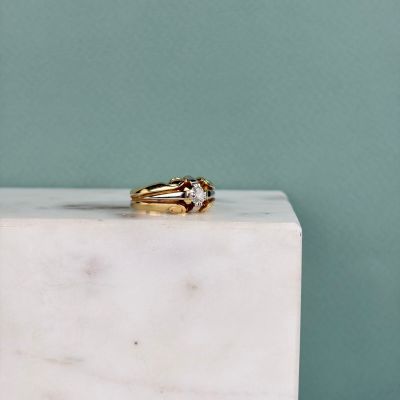 une image représentant une bague en or posée sur un bloc de marbre blanc