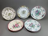 quatre assiettes ornées de motifs floraux sont disposées sur un fond gris